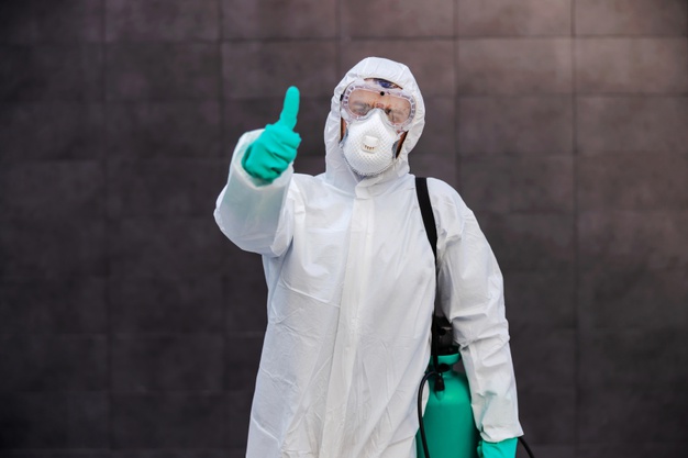 hombre-uniforme-protector-esteril-guantes-goma-que-llevan-rociador-desinfectante-mostrando-pulgares-arriba-mientras-pie-al-aire-libre-prevencion-propagacion-concepto-virus-corona_232070-10325